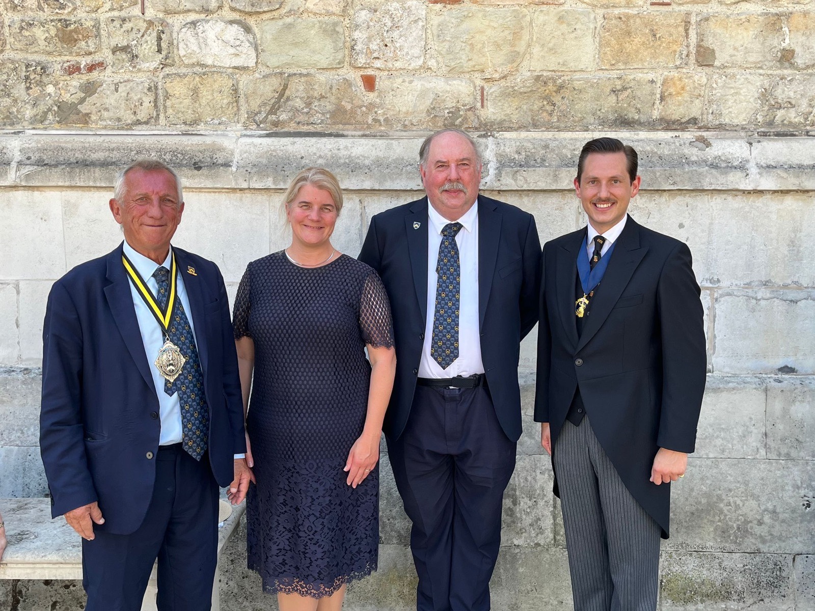 The four Ale Conners of the City of London standing together in front of a stone wall after the election at Common Hall; Liam Randall stands on the right in morning dress, wearing the badge of office.
