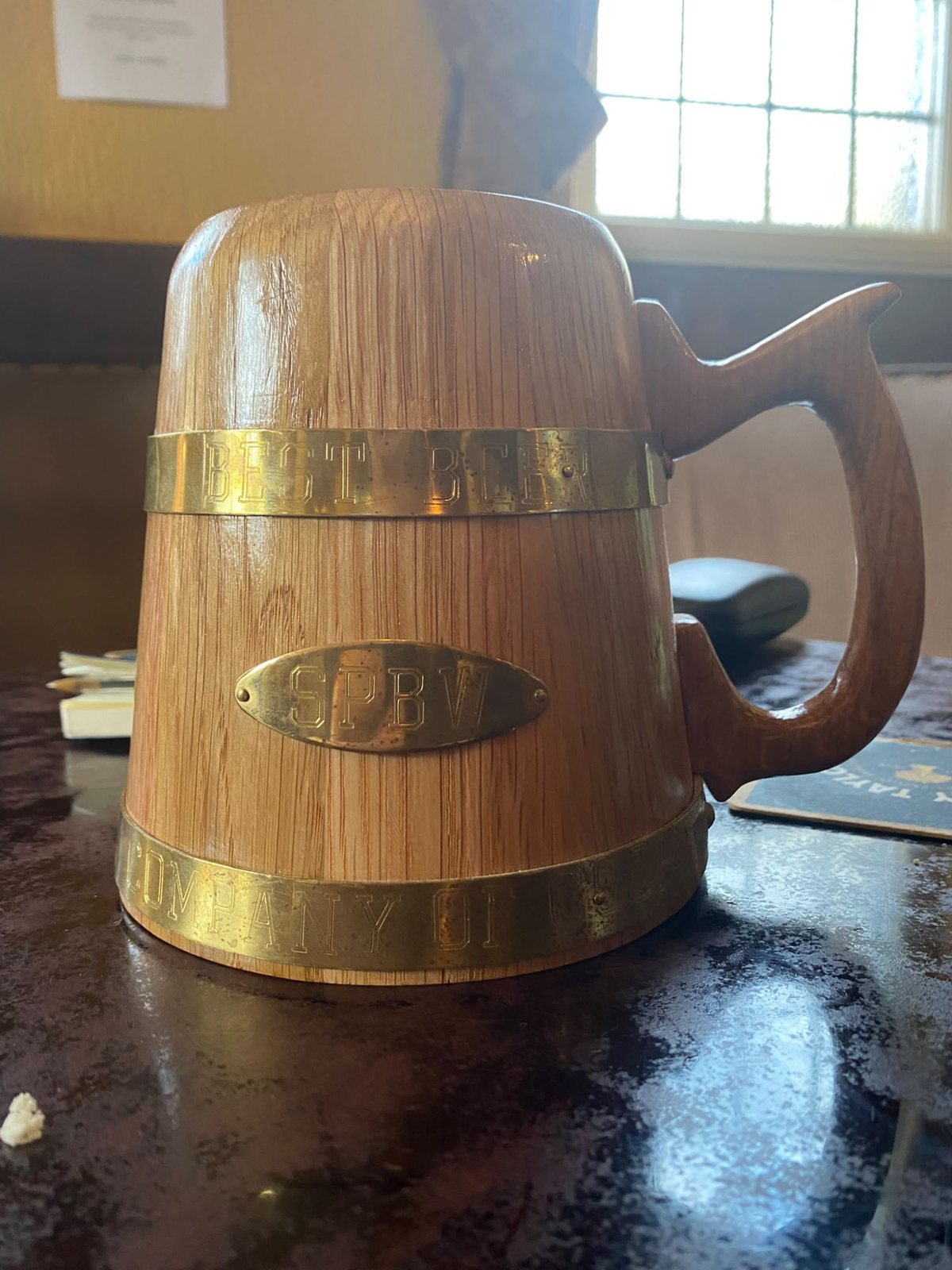 The Best Beer from the Wood trophy on a pub table: a small tankard of oak staves bound with two brass hoops, the upper band stamped Best Beer and an oval brass plate stamped SPBW.