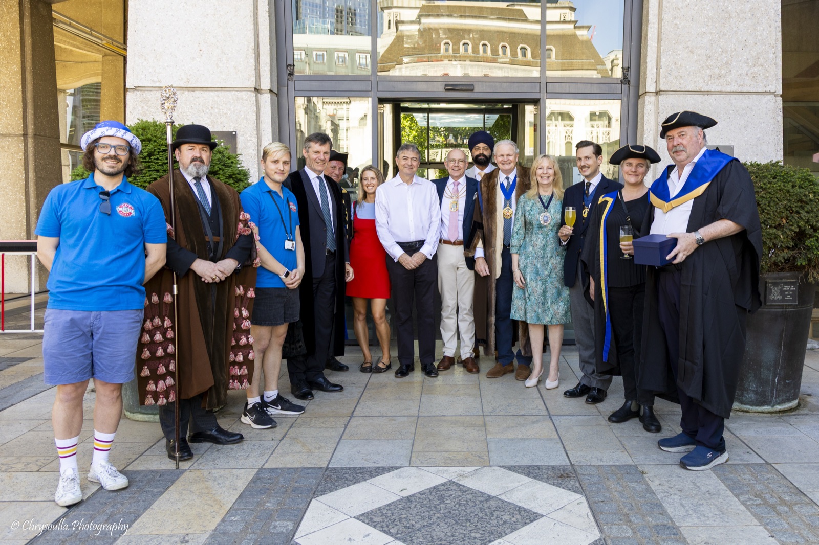 The Brewers&rsquo; Company and the Lady Mayor&rsquo;s party pose together at the entrance to the Guildhall complex on festival day &mdash; festival staff in blue polo shirts, a staff-bearer in a bowler hat and brown tasselled gown, liverymen in ceremonial dress and Ale Conners in tricorn hats; Liam Randall stands third from the right, tricorn on and glass in hand.